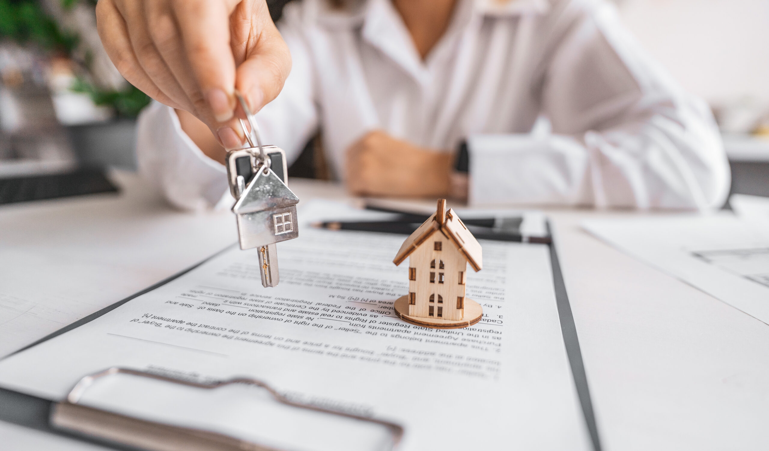 Woman real estate agent gives keys paperwork and miniature house model. Concept of buying apartment, rental contract signing, trusted agency service and modern housing ownership.