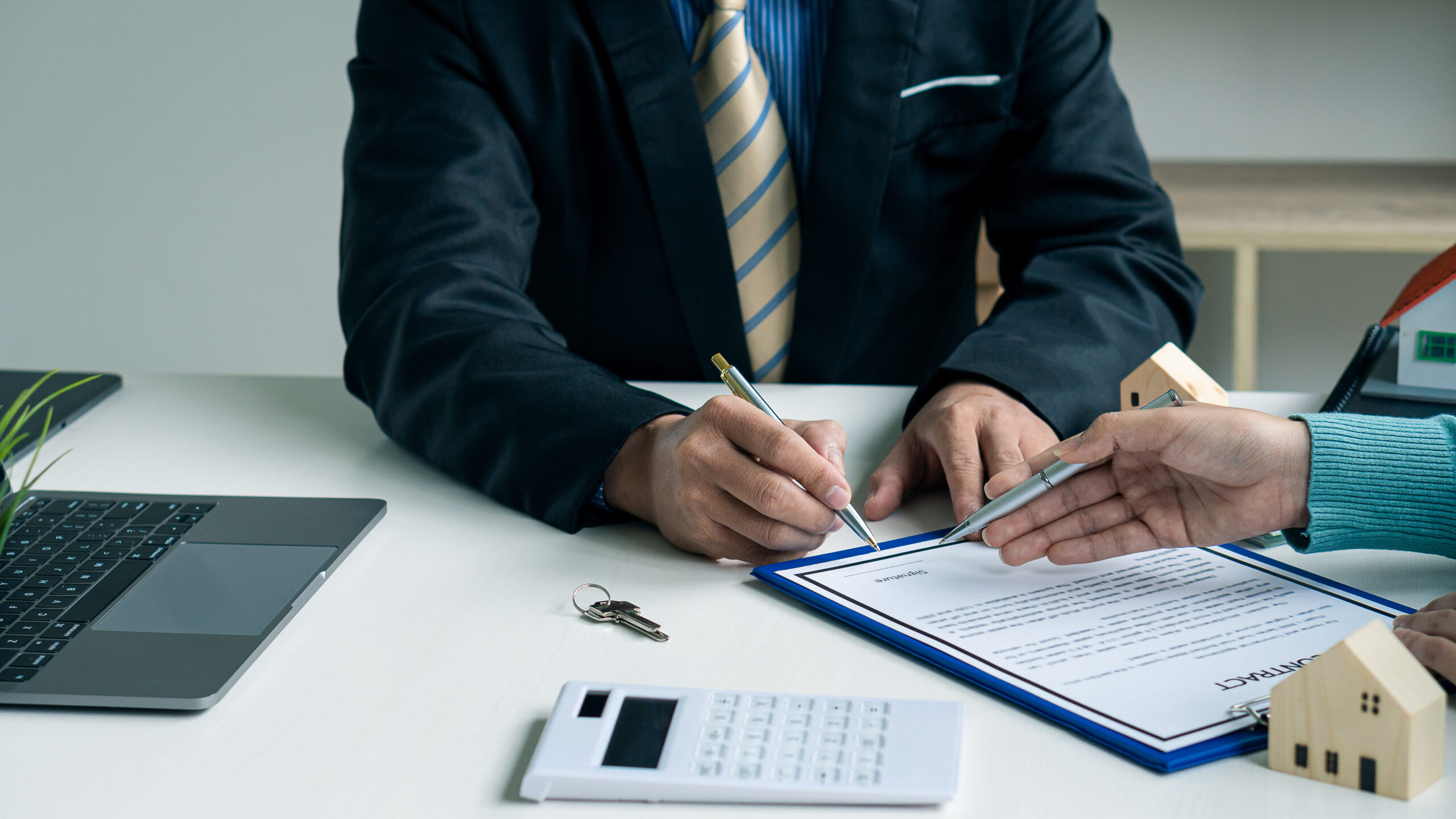 Real estate professionals and clients discussing home purchases, insurance or real estate loans. Home sales agents sit at the office with new homebuyers in the office.