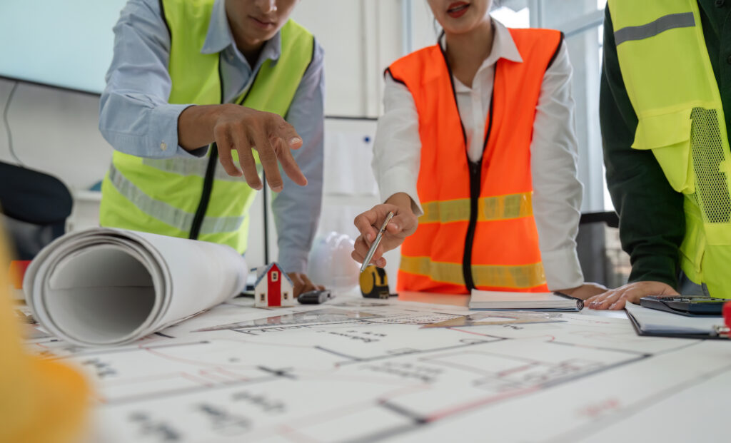 Construction team pointing at project plans and discussing layout details in a professional office setting